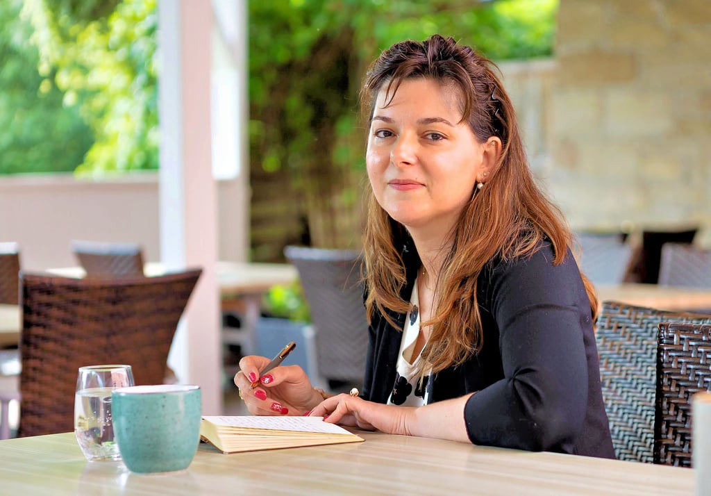 Lucia Tran schreibt im Biergarten ihres Restaurants Gedanken in ihr Notitzbuch, später bearbeitet sie die Notizen weiter.