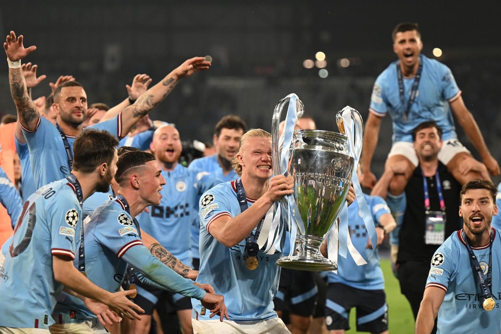 Manchesters Erling Haaland (M) jubelt mit der Trophäe nach dem gewonnenen Spiel.