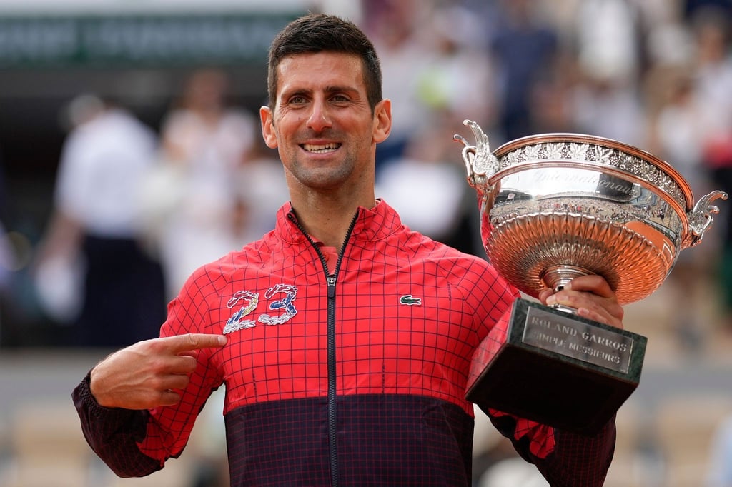Novak Djokovic zeigt auf die 23 auf seiner Trainingsjacke und jubelt über seinen Sieg.