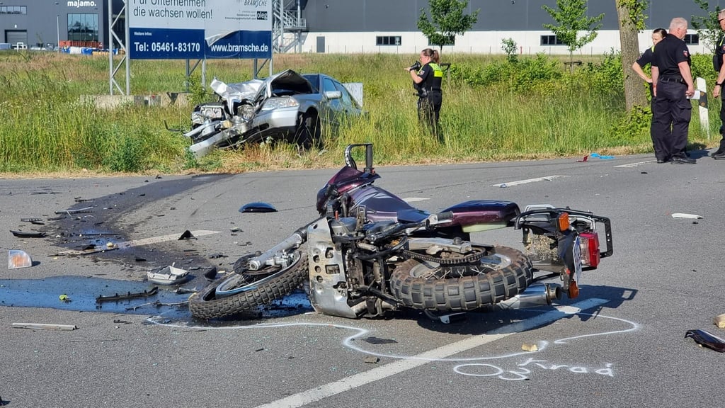 Ein Motorrad liegt nach einem Unfall auf der Straße, im Hintergrund das beteiligte Auto.