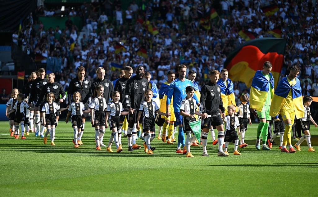 Die Spieler kommen mit den Einlaufkindern in das Stadion.