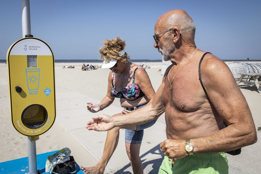 Ein Spender mit kostenlosem Sonnenschutz steht an einem niederländischen Strand, um Besucher vor Sonnenbrand zu schützen.