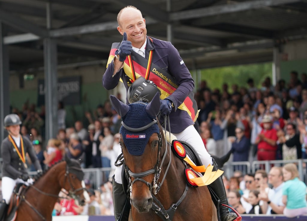 Der deutsche Vielseitigkeitsreiter Michael Jung jubelt auf seinem Pferd.