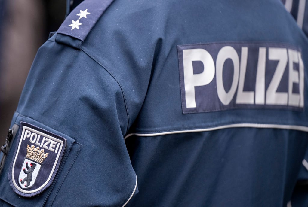 Die Aufschrift "Polizei" und das Wappen der Berliner Polizei auf der Uniform eines Polizeibeamten.