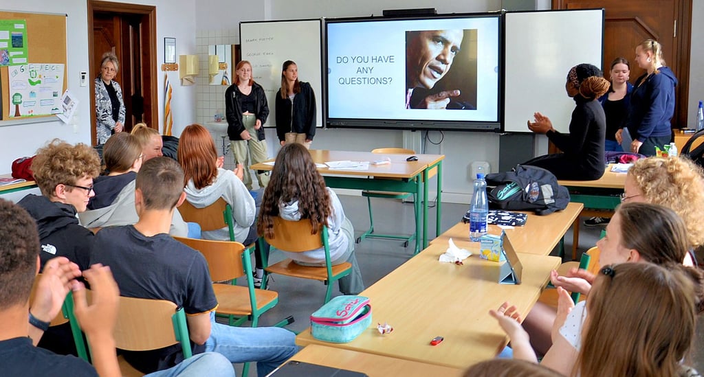 Für ihre Präsentation ernten Phoebe (an der digitalen Tafel von links), Lotta, Jolina und Johanna Applaus - sowohl von Vivian, die wie alle Gäste von der Insel nur in Englisch kommunizierte - als auch von den Achtklässlern, die das Ergebnis der vier Intensiv-Sprachtage in Staßfurt ebenfalls verfolgten.