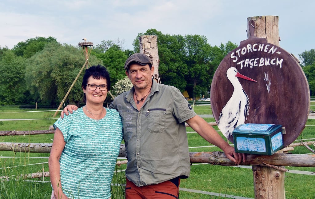 Karin und Rico Bendix an ihrem Storchennest (im Hintergrund) und am Storchentagebuch am Radweg bei Bottendorf.