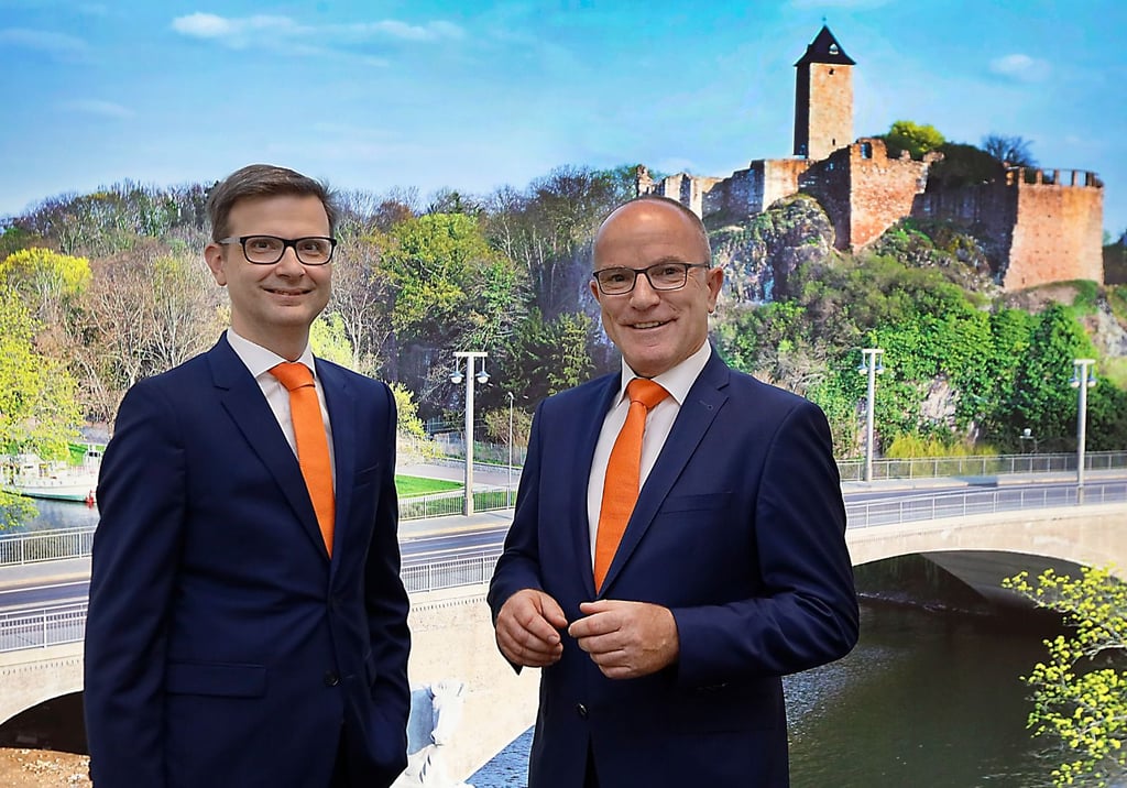 Auch die Fotos am Stammsitz in der Wilhelm-Külz-Straße künden von regionaler Verankerung: Sascha Gläßer und Thomas Kaul, Vorstandsvorsitzender und Vorstand der Volksbank, vor einem Wandbild mit Saale, Giebichensteinbrücke und Oberburg