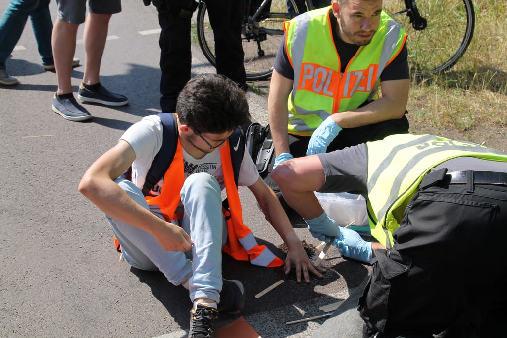 Mit viel Fingerspitzengefühl lösten Polizeibeamte aus Magdeburg am Montag in Halle die festgeklebten Klimaaktivisten von der Straße.