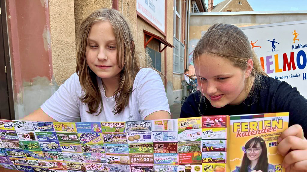 Jasmin Radelhof (links) und Chayenne-Marie Anton stöbern durch den neuen Bernburger Ferienkalender.