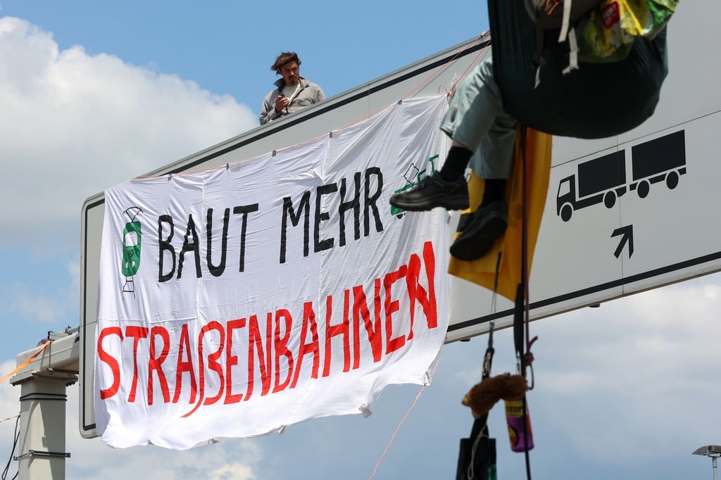 Aktivisten befestigen ein Transparent an einer Schilderbrücke.
