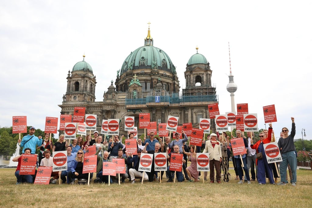 Drehbuchautorinnen und Drehbuchautoren solidarisieren sich bei einer Demonstration vor dem Berliner Dom mit ihren streikenden US-Kollegen.