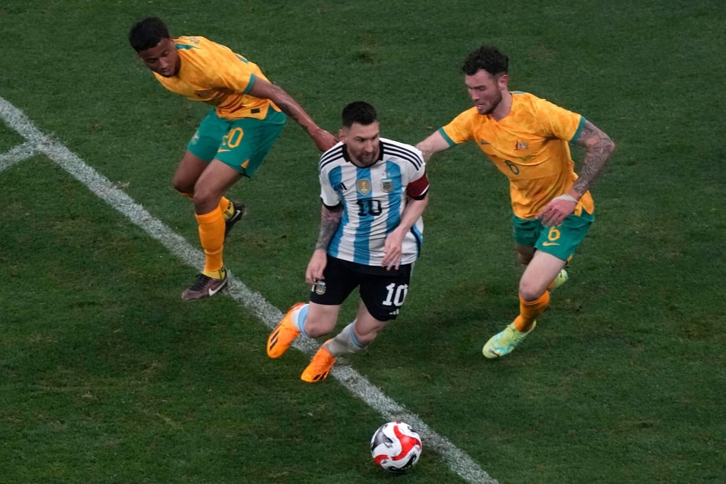 Lionel Messi (M) setzt sich im Dribbling gegen zwei Gegenspieler durch.