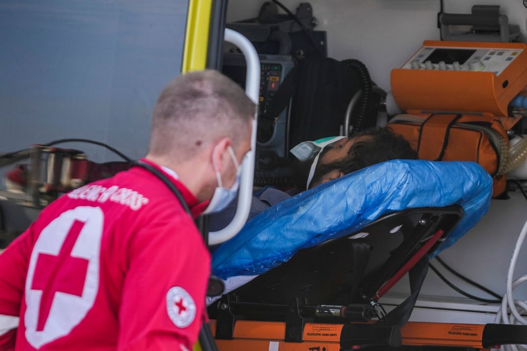 Ein Sanitäter steht im Hafen von Kalamata neben einem verletzten Überlebenden des Schiffsunglücks.