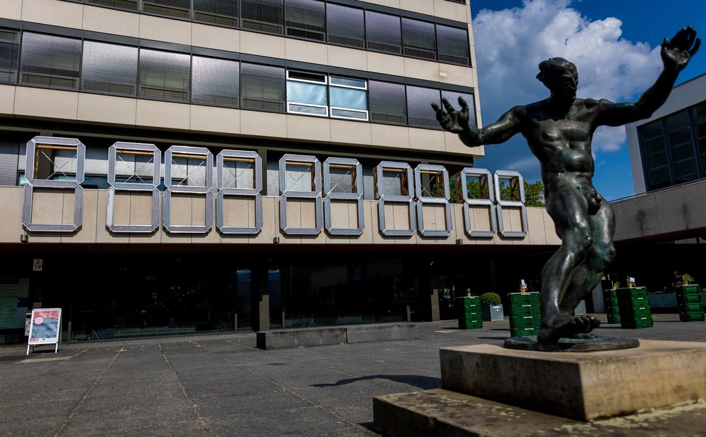 Eine „ClimateCrisisClock“ hängt am Forumsgebäude der Technischen Universität (TU) Braunschweig hinter einer Dionysos-Skulptur.