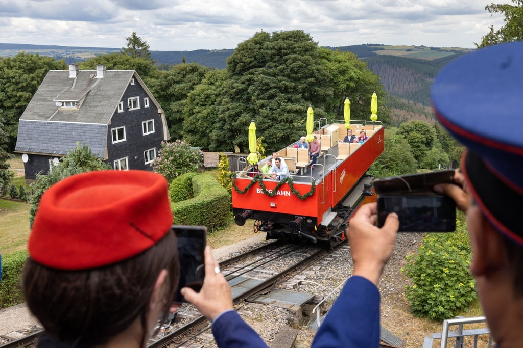 Menschen in historischen Bahnuniformen fotografieren vor Beginn des Jubiläumsfests 100 Jahre Bergbahn Oberweißbach.