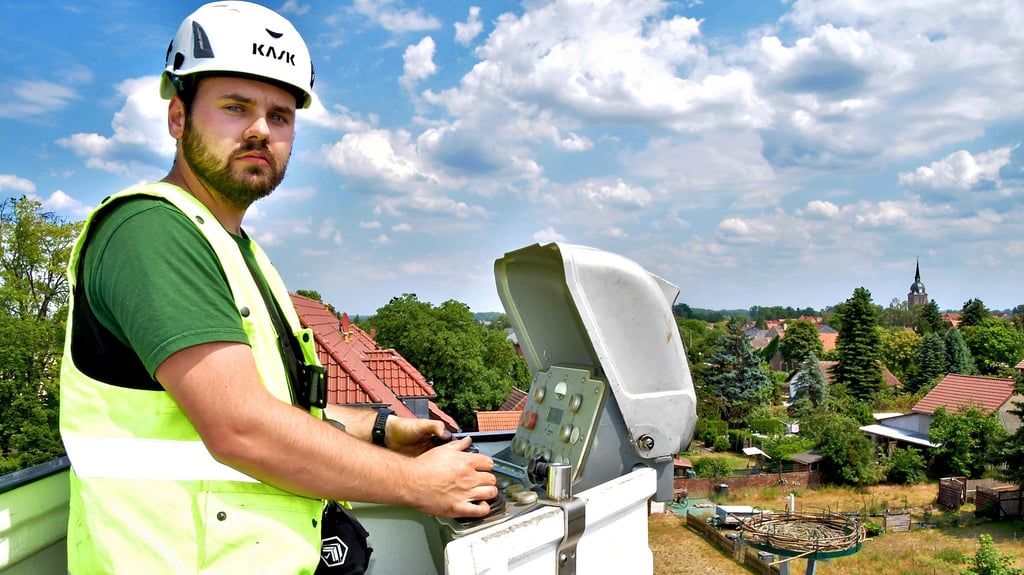 Es ist vollbracht. Adrian Heinemann, Regionalmonteur der Avacon, hat die Nestunterlage per Hebebühne auf den Mast gesetzt. Die Störche haben den Männern vom naheliegenden Schornstein des alten Bahnhofs bei der Arbeit zugeschaut.