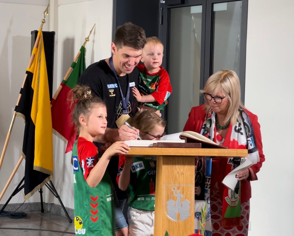 SCM-Handballer Piotr Chrapkowski mit seinen Kindern im Rathaus Magdeburg: Der Champions-League-Gewinner trägt sich in das Goldene Buch der Stadt ein, neben ihm steht OB Simone Borris