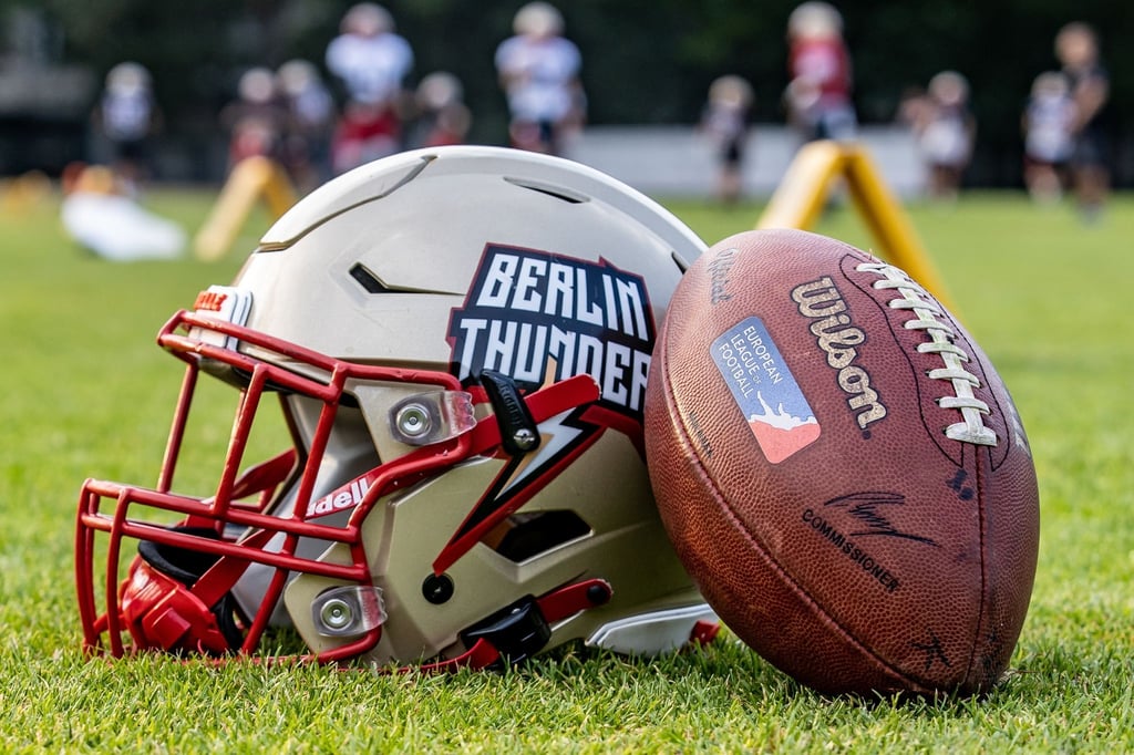 Ein Helm und ein Football liegen auf dem Rasen.