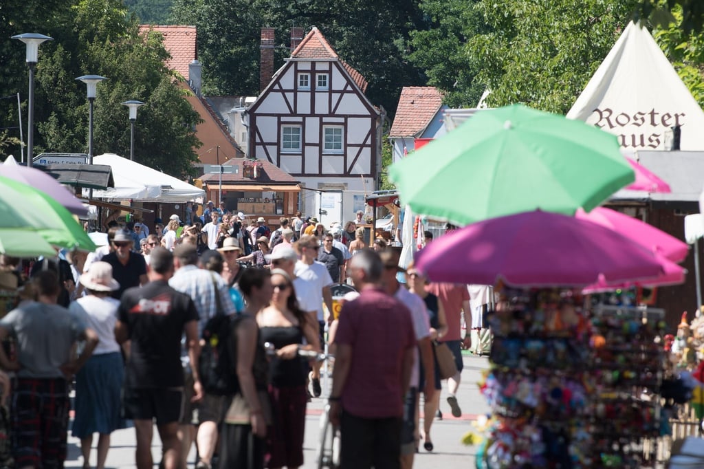 Besucher des Elbhangfests gehen an Verkaufsständen entlang.