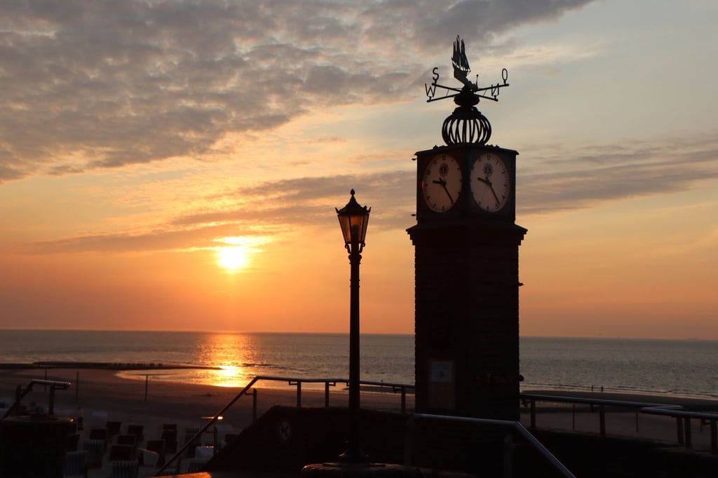 Die Sonne geht hinter der sogenannten Puddinguhr an der Strandpromenade der Insel Wangerooge unter. An den längsten Tagen des Jahres locken einige Ostfriesische Inseln ihre Gäste mit Kultur- und Freizeitangeboten.