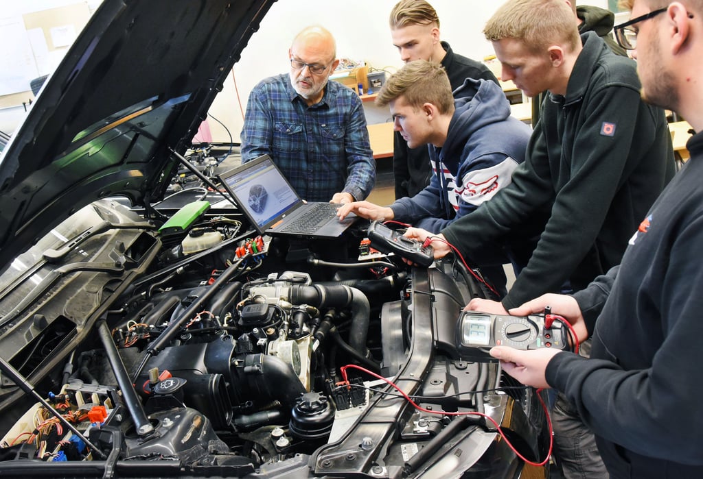 Angehende KFZ-Mechatroniker bereiten sich auf eine Fahrzeugdiagnose vor.