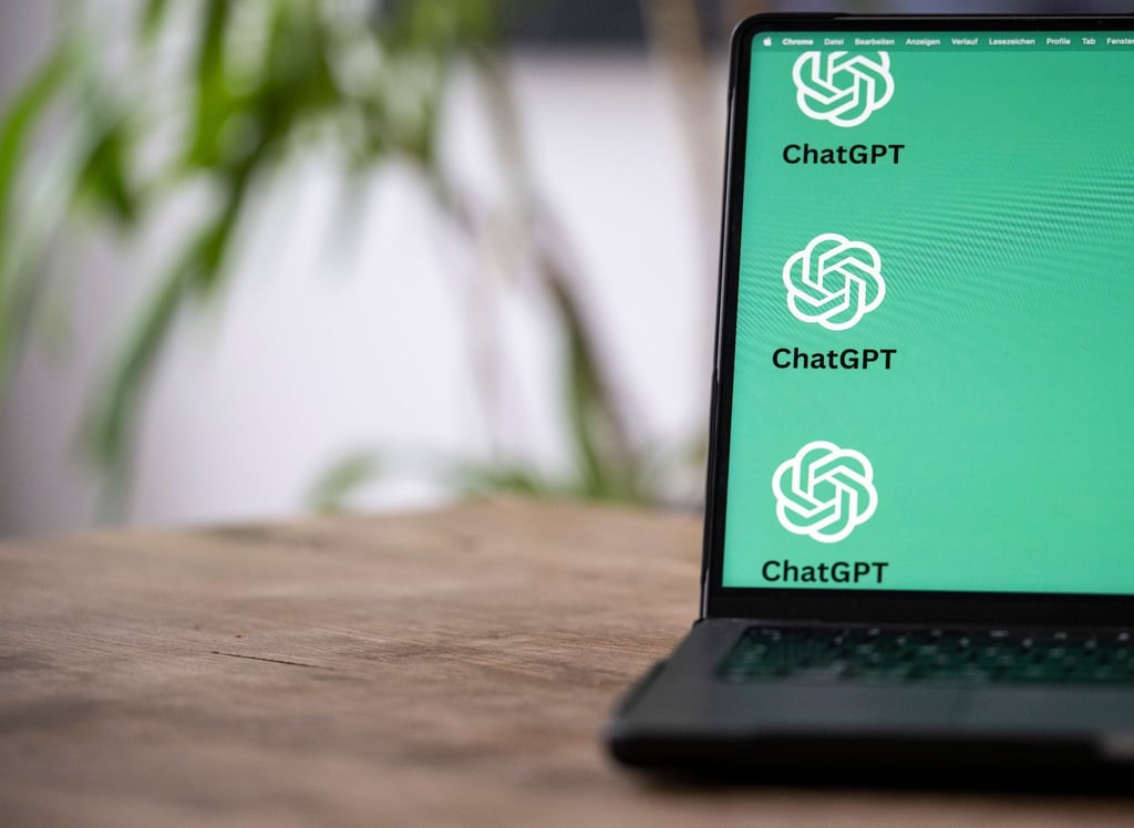 Die ChatGTP-Logos auf dem Monitor des Laptops zeigen, dass hier mit Künstlicher Intelligenz gearbeitet wird.