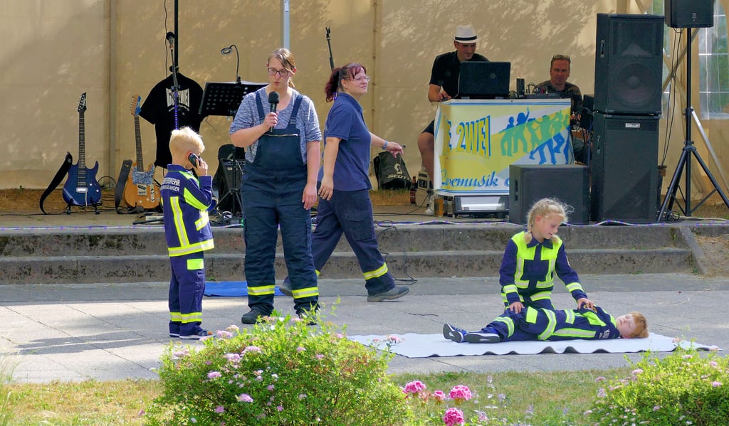 Der Feuerwehr Nachwuchs zeigt den Besuchern des Parkfestes in Mühlanger, dass Erste Hilfe kinderleicht ist. Lena dreht den verletzten Leopold in die stabile Seitenlage, während Till die Rettung ruft.