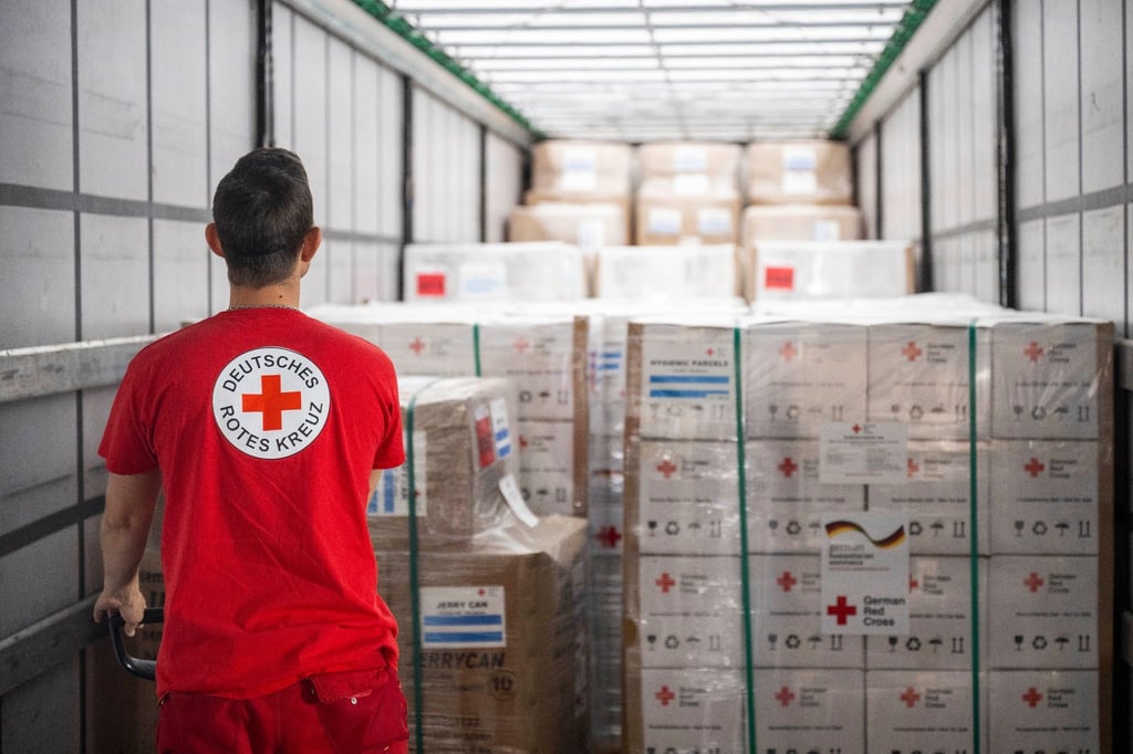 Ein Mitarbeiter vom Deutschen Roten Kreuz verlädt Hilfsgüter in einem Logistikzentrum vom DRK.