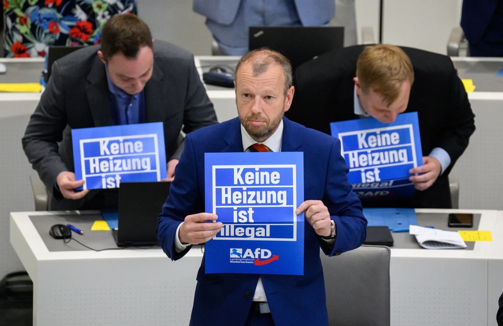 Stefan Marzischewski-Drewes (AfD) und weitere Fraktionsmitglieder halten im niedersächsischen Landtag während der Debatte Schilder mit Aufschrift „Keine Heizung ist illegal“.