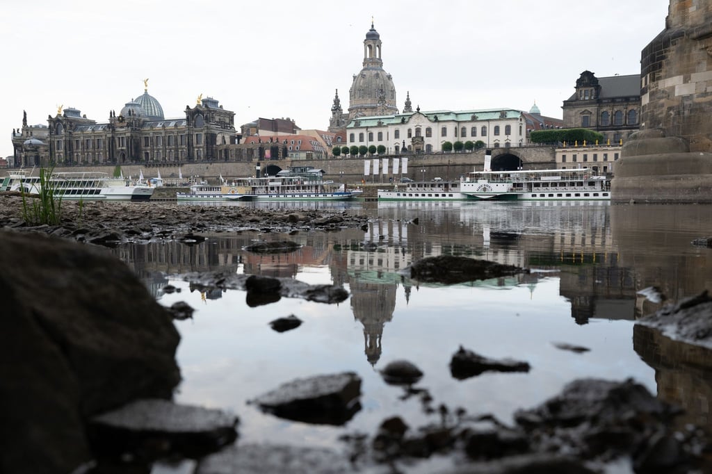 Die Frauenkirche spiegelt sich am Ufer der Elbe unterhalb der Augustusbrücke im Wasser.