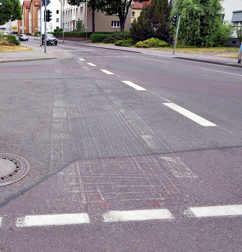 In der August-Bebel-Straße sind noch Spuren der alten roten Radwegmarkierung an einer Einmündung zu erkennen.