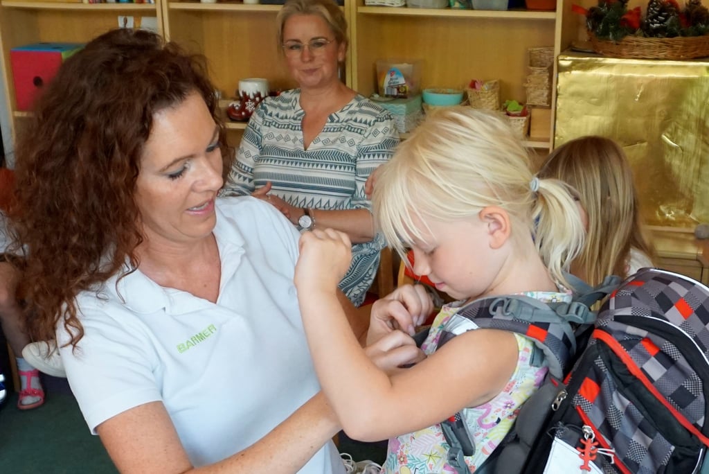 Cynthia Pietsch-Stein hilft Dorothea, den Brustgurt des Schulranzens zu schließen.