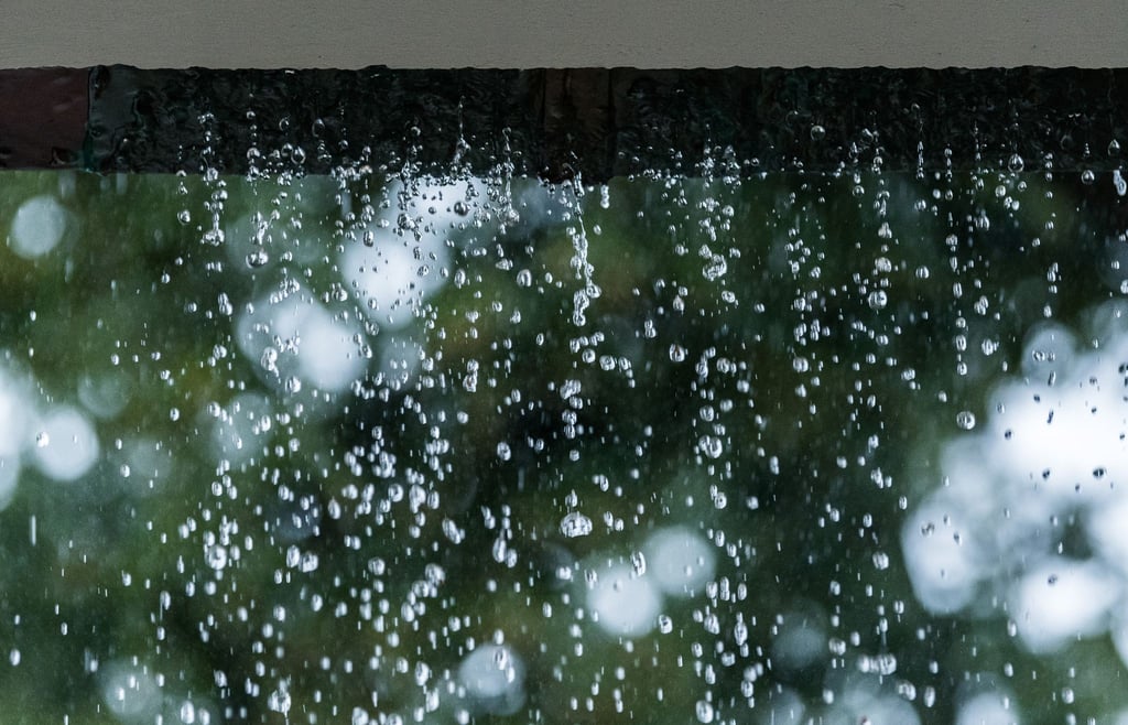 Statt zum Abfluss schießt das Regenwasser während eines Unwetters an einer verstopften Regenrinne hinunter und sucht sich seinen Weg.