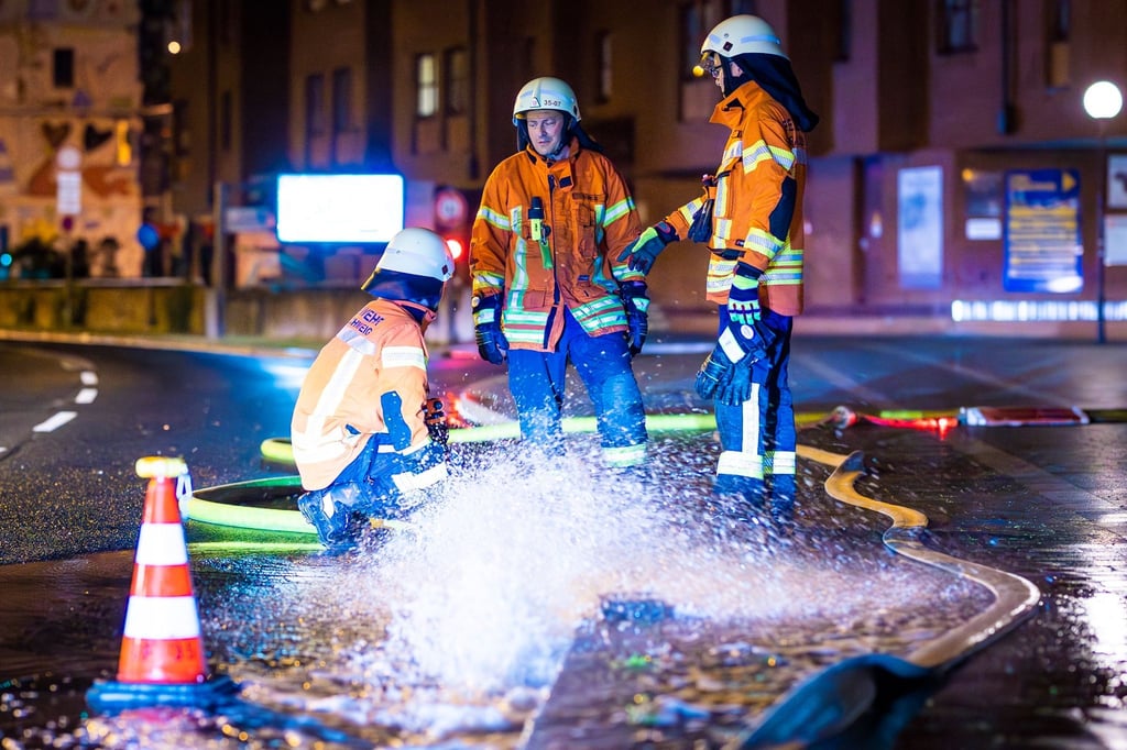 Einsatzkräfte der Feuerwehr pumpen in der Nacht Regenwasser aus einem Keller auf die Straße.