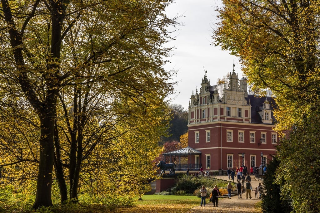 Spaziergänger sind am Neuen Schloss im Fürst-Pückler-Park in Bad Muskau unterwegs.