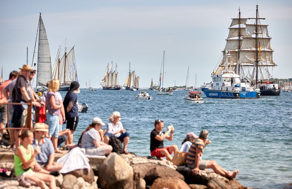 Menschen verfolgen an der Förde die Windjammerparade.