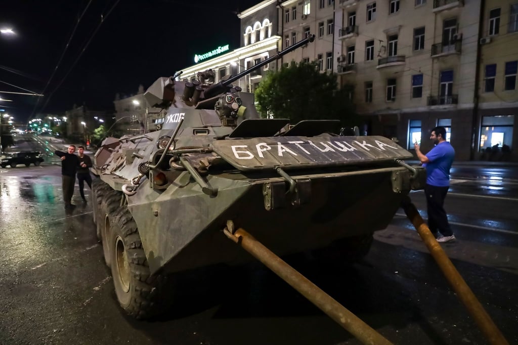 Menschen gehen um ein gepanzertes Fahrzeug des Militärunternehmens Wagner Group mit der Aufschrift „Brother“ herum, bevor sie ein Gelände am Hauptsitz des Südlichen Militärbezirks auf einer Straße in Rostow am Don verlassen.