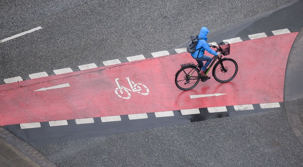 Eine Frau fährt bei Regen mit einem Fahrrad.