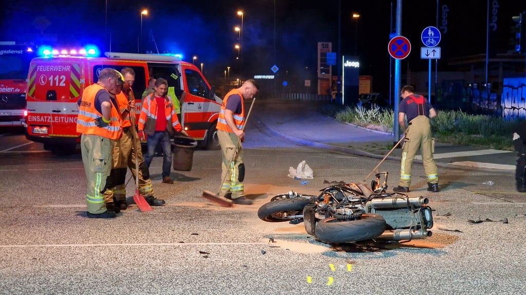 Feuerwehrleute reinigen eine Kreuzung auf der noch das verunfallte Motorrad liegt.