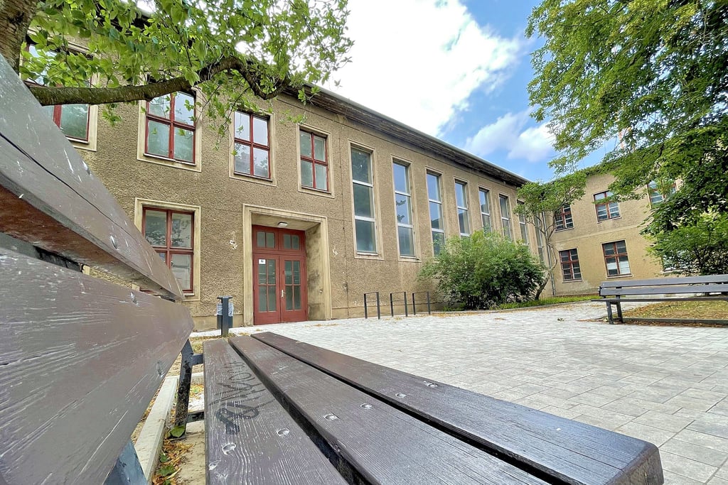 Mit Bänken zum Verweilen und schattenspendenden Bäumen davor wirkt die Turnhalle an der Brandenburger Straße einladend. Doch bis sie umgenutzt werden kann, muss noch renoviert werden.