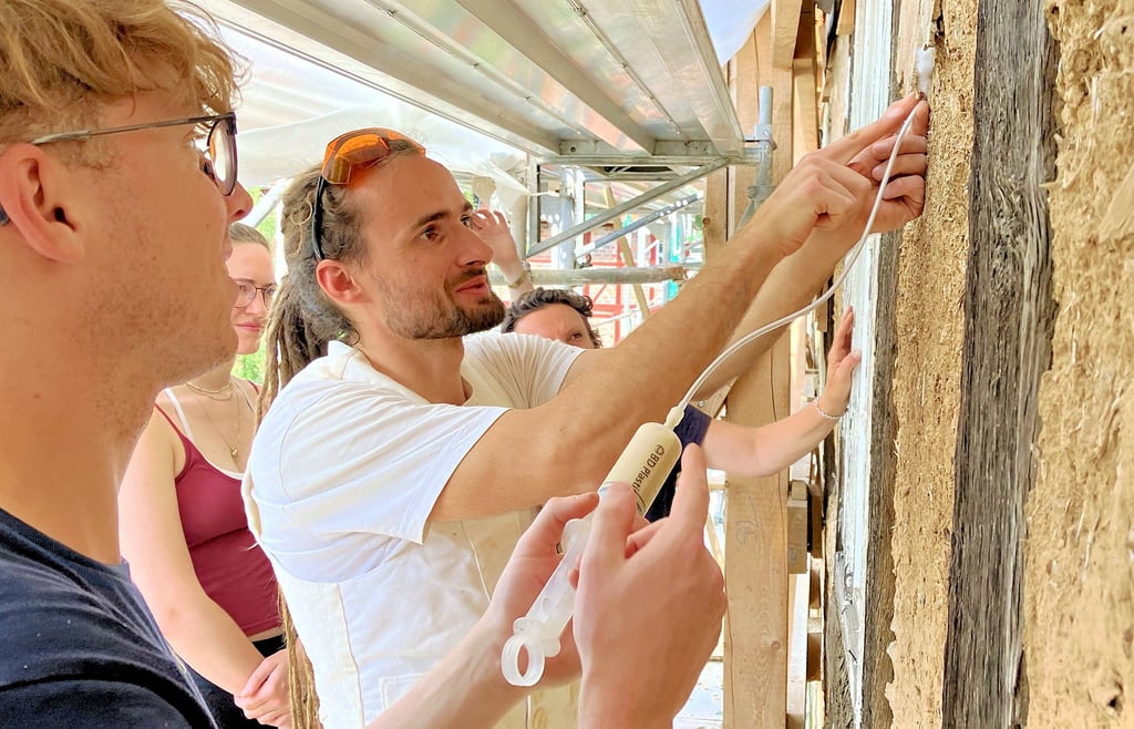 Maik Sommerfeld zeigt Studenten der Universität Bamberg, wie mit einer angerührten Masse alter Putz gerettet wird.