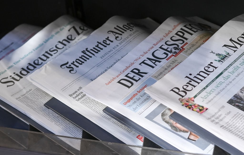 Zeitungen liegen in einer Auslage in einem Zeitschriftenladen.