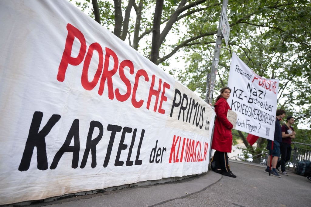 Demonstranten mit Plakaten vor Beginn der Porsche-Hauptversammlung in Stuttgart.