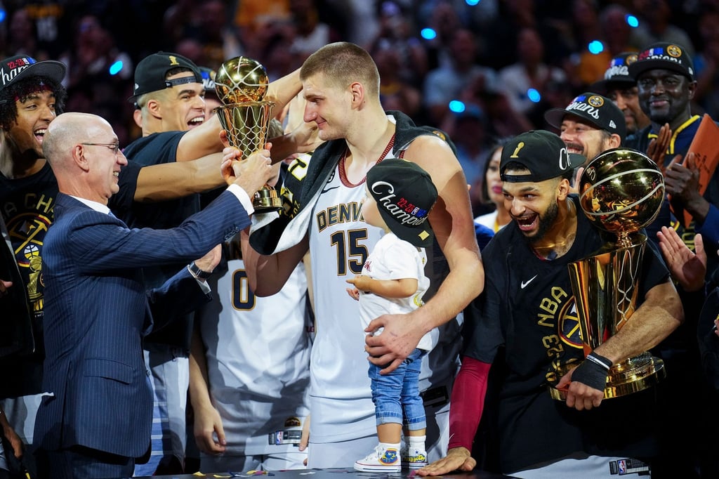 NBA-Commissioner Adam Silver (l) überreicht die MVP-Trophäe an Nuggets-Center Nikola Jokic (M.).