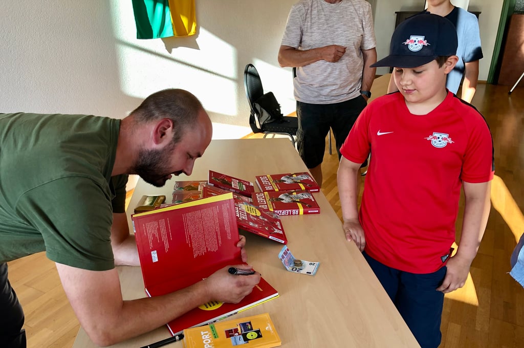 Autor Ullrich Kroemer schreibt für den 9-jährigen RB-Fan Lasse Lassek aus Goldschau eine Widmung ins Buch.