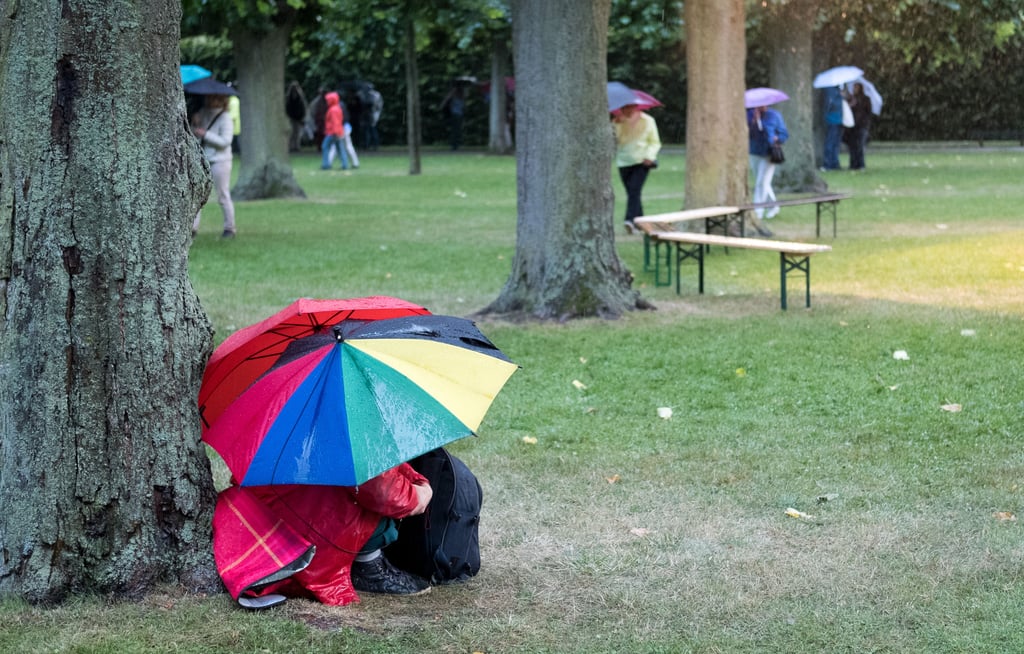 Besucher mit Regenschirmen suchen bei Gewitter Schutz unter einem Baum. Auch in den kommenden Tagen muss in Sachsen-Anhalt mit Gewittern gerechnet werden.