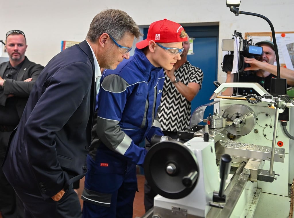Wirtschafatsminister Robert Habeck schaut einem Lehrling an der Drehbank in der in der Ausbildungsstelle des Energieunternehmens LEAG am Standort vom Braunkohlekraftwerk Jänschwalde über die Schulter.