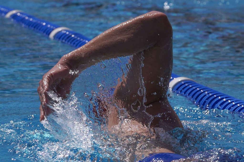 Ein Mensch schwimmt in einem Freibad Bahnen.