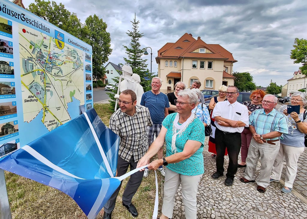 Regina Meyer von Heimat- und Bergbauverein und Vizebürgermeister Martin Blümel enthüllen die neue Tafel vor dem Gemeindehaus. Sie lädt ein, die „Häusergeschichten“ im Ort zu erkunden.