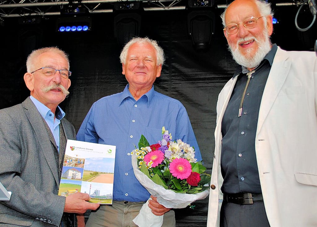 Eike Trumpf (links) und Norbert Lazay (rechts) gratulieren Lothar Täuscher aus Kamern zur besten Ortschronik des Landkreises Stendal.